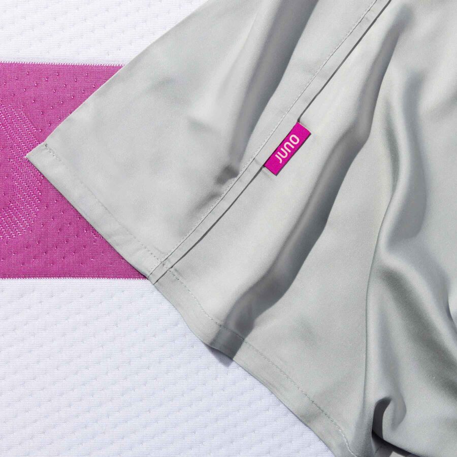 The top sheet of Juno Bamboo Sheets - showing the berry-coloured Juno brand tag