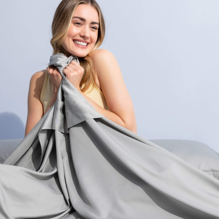 Woman smiling and holding the top sheet of Juno Bamboo Sheets