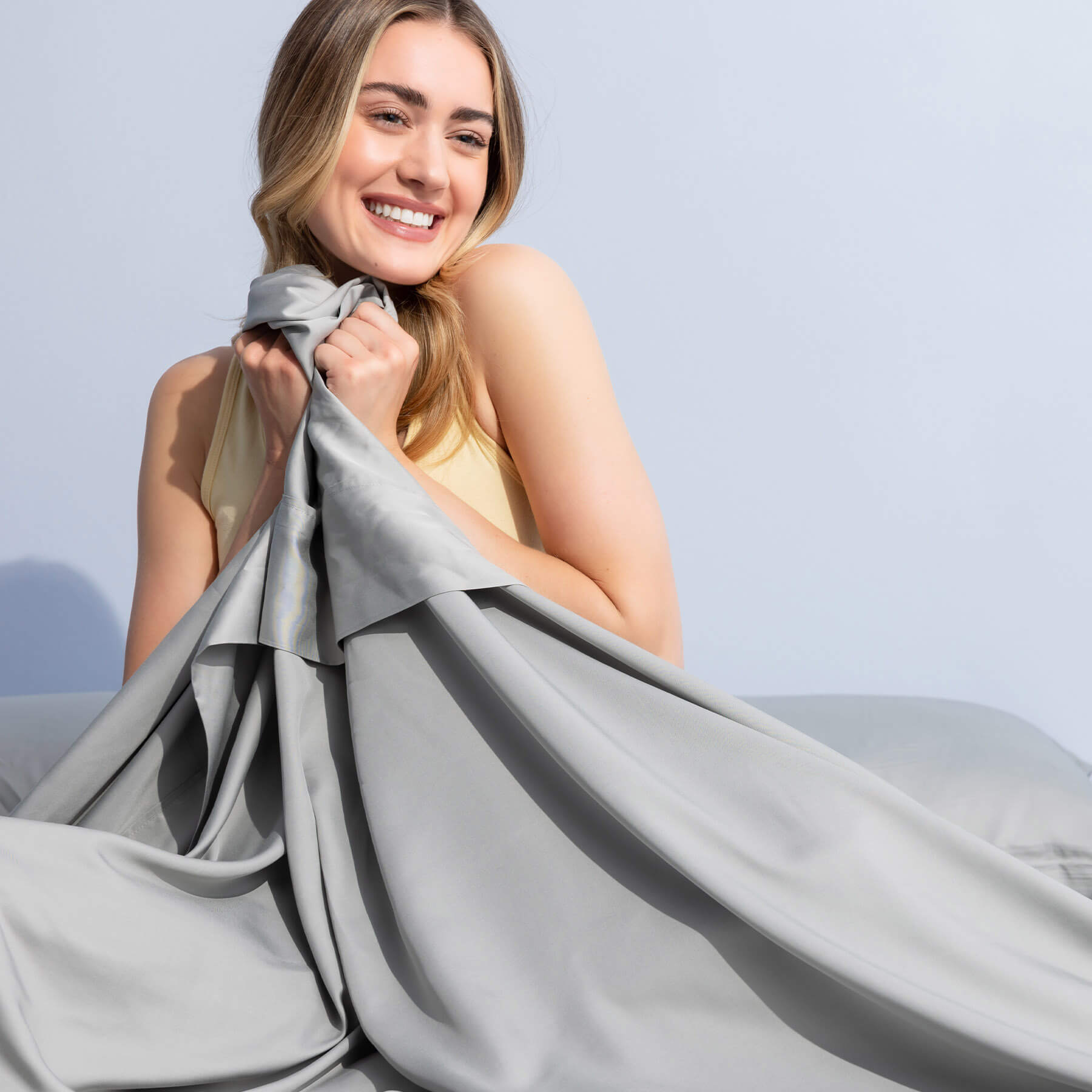 Bamboo-Sheets-Carousel-6 Woman smiling and holding the top sheet of Juno Bamboo Sheets