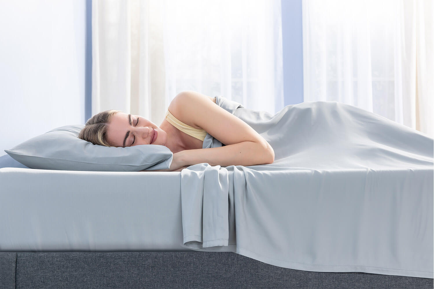 Femme dormant paisiblement, avec un ensemble de draps en bambou Juno gris pâle