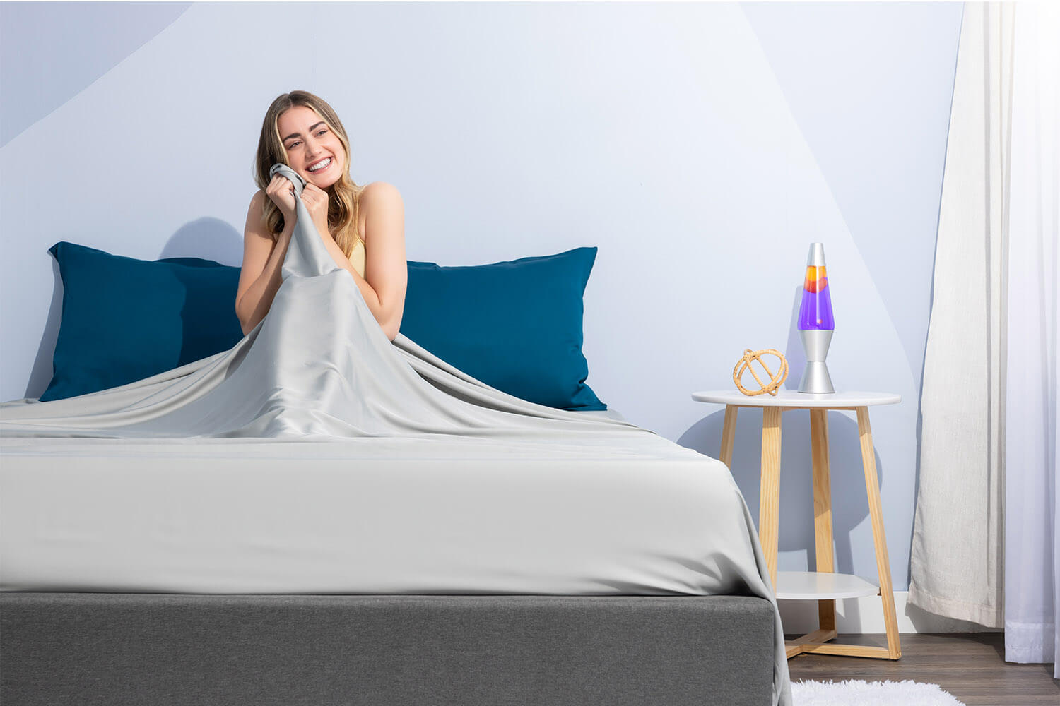 Woman smiling and touching her set of Juno Bamboo Sheets
