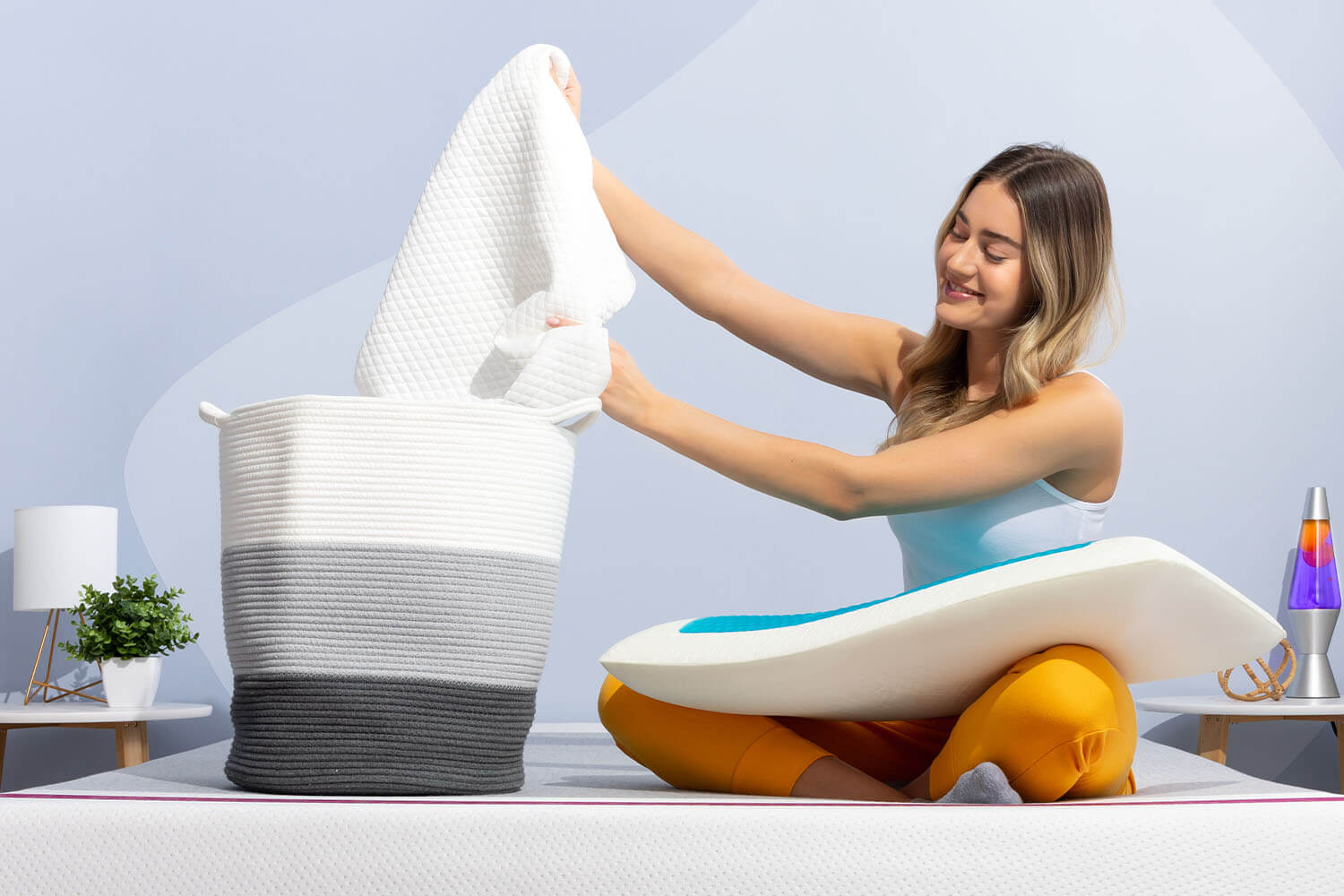 Femme plaçant la housse lavable en machine oreiller avec gel rafraîchissant Juno dans un panier de lavage