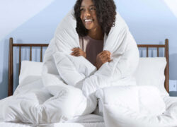 Woman smiling and hugging herself with a Juno Down Alternative Duvet