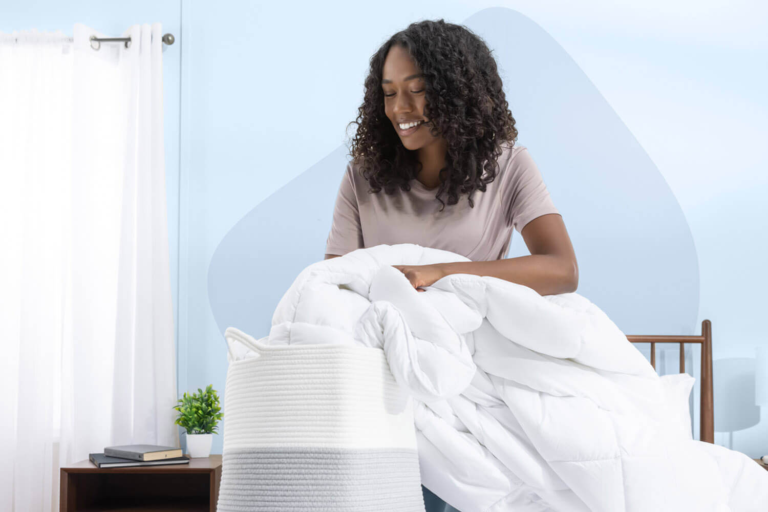 Femme mettant une couette en duvet synthétique Juno dans le panier de lavage