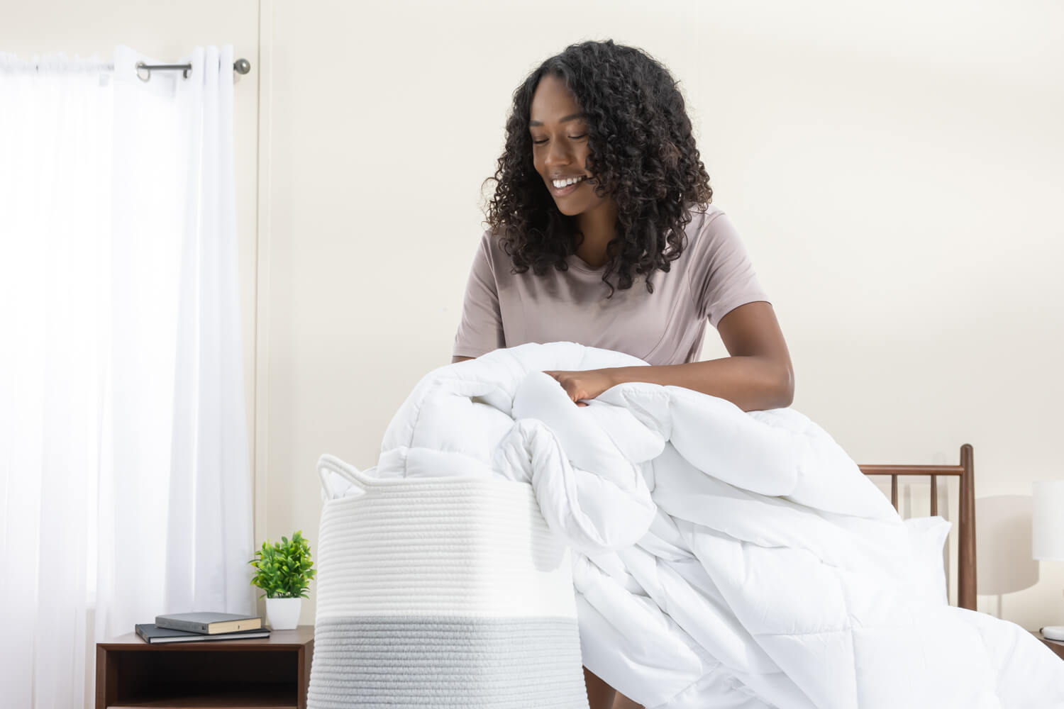 Une femme met sa couette en duvet synthétique dans le panier à linge.