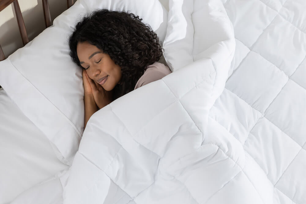 Woman sleeping peacefully, covered by her down alternative duvet.