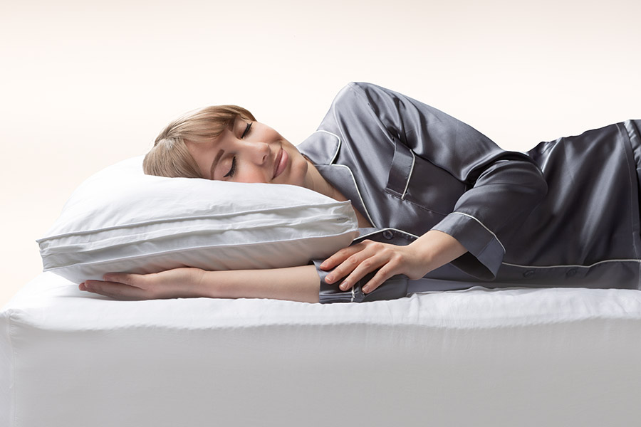 Une femme dort paisiblement sur le ventre avec la tête sur l’oreiller en microfibre Juno.