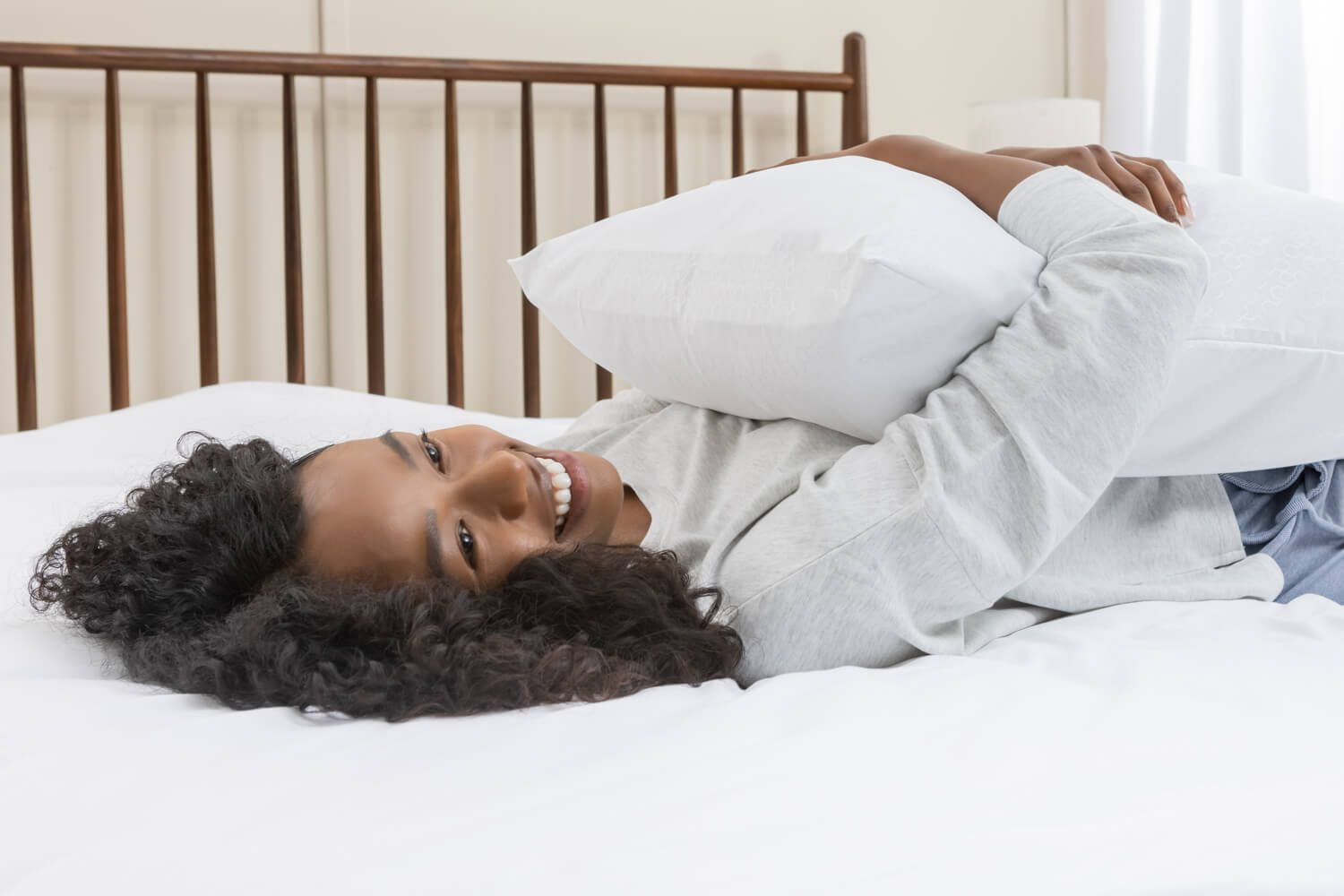 Une femme est étendue sur le dos sur son lit et tient un oreiller avec la protection de la barrière WaterShield.