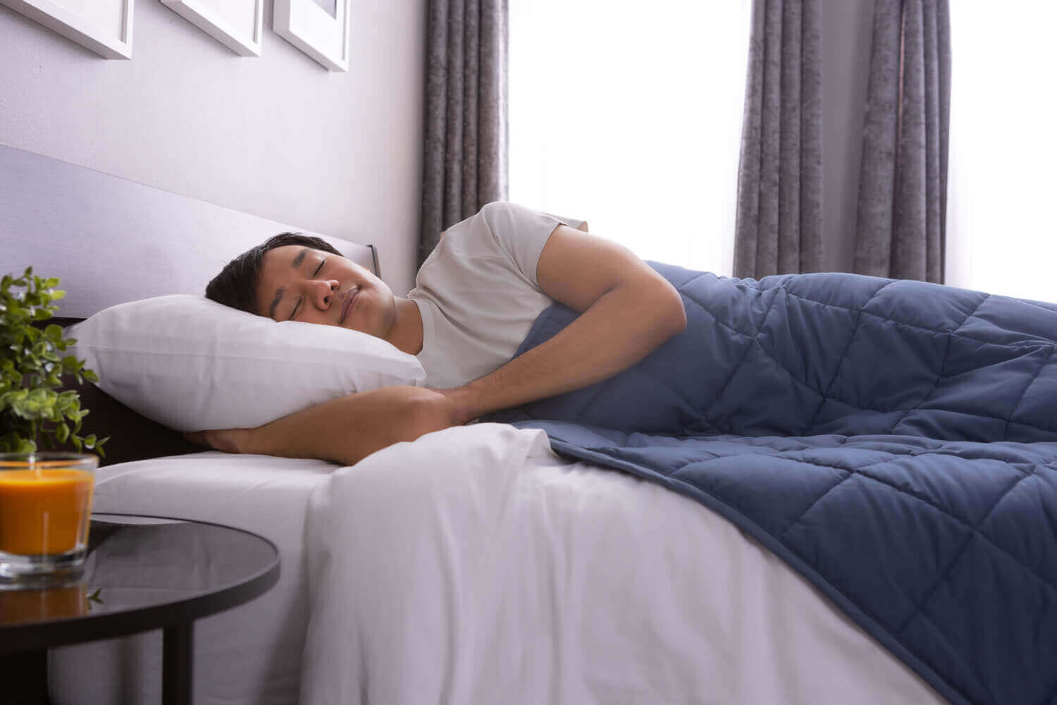 Un homme se repose dans son lit, la couverture lestée classique recouvrant son corps.