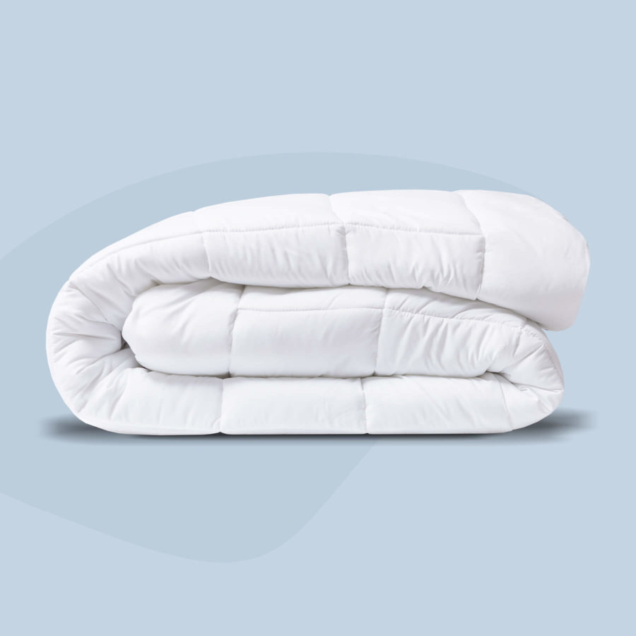 Une couette alternative en duvet toutes saisons est soigneusement pliée sur un fond bleu clair.
