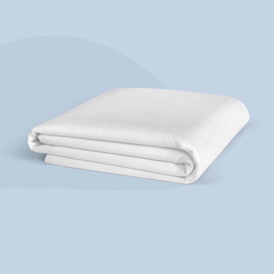 A white mattress protector from Juno.ca sits neatly folded on a light blue background.