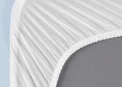 Une vue du coin inférieur d'un protège-matelas Juno, montrant l'élastique extensible parfaitement ajusté sur un matelas Juno.