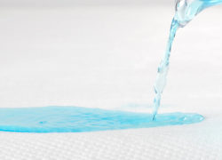 Blue liquid is poured onto the Juno mattress protector to show it's protective and absorbent qualities.