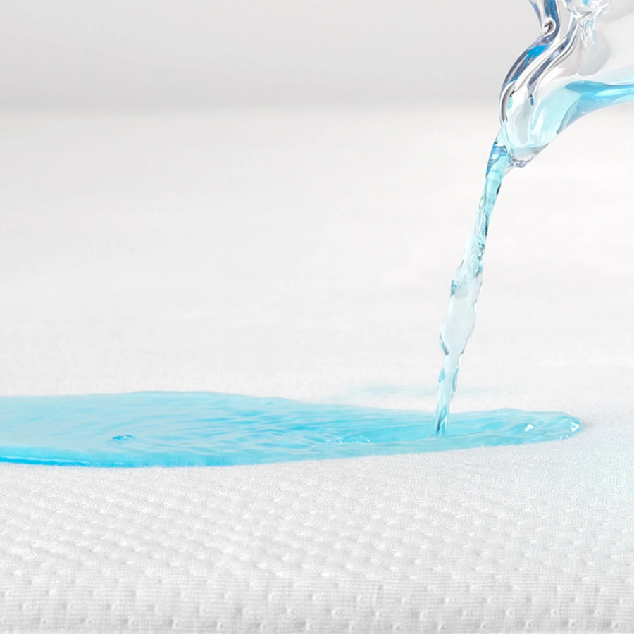 Un liquide bleu est versé sur le protège-matelas Juno pour montrer ses qualités protectrices et absorbantes.