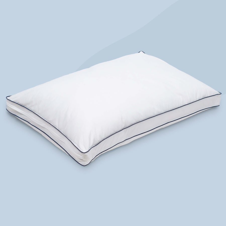 An angled view of a Juno Adjustable Memory Foam Pillow sitting against a light blue background.