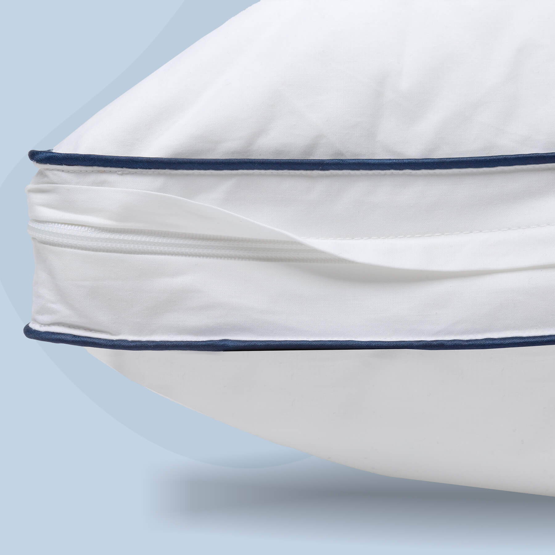 JB-MemoryFoamPillow-Carousel-4 A close up of the zipper on the Juno Adjustable Memory Foam Pillow. The zipper is surrounded by two dark blue seams and the pillow is set against a light blue background.