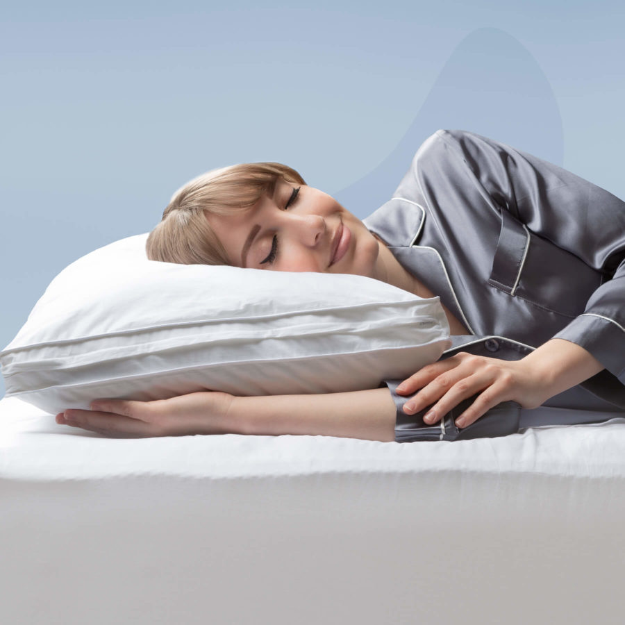 A woman smiles as she rests her head on a Juno Microfibre pillow.