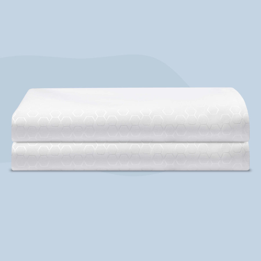 Two Pillow protectors with reflective hexagonal patterns sit on top of one another, neatly folded, against a light blue background.