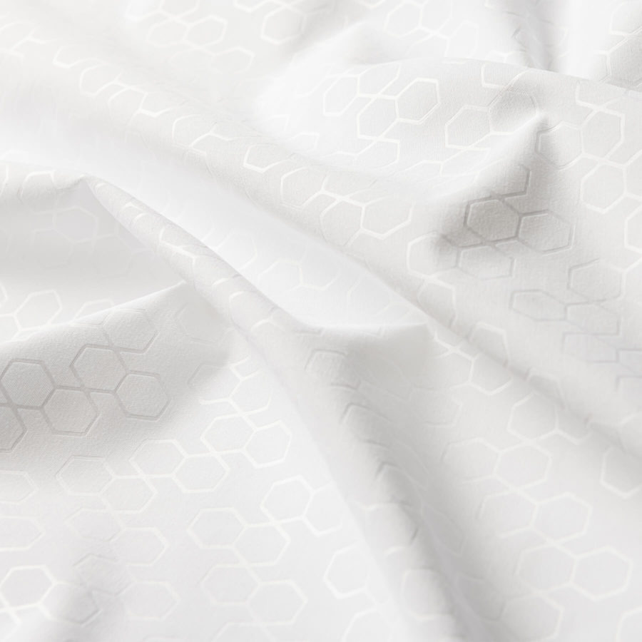 A close up of a hexagonal pattern shining against the white fabric on the Juno Pillow Protector.