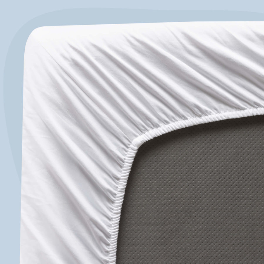 A bottom-corner view of a Juno sateen sheet set, showcasing the stretchy elastic that snugly fits the sheets to your mattress.