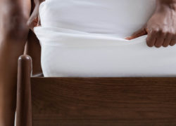 Une femme étend un drap de satin Juno sur son matelas.