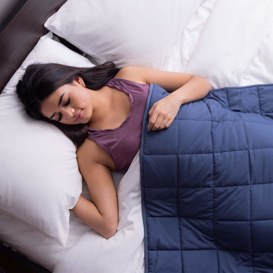 Femme dormant paisiblement avec une couverture pondérée classique drapée sur son corps