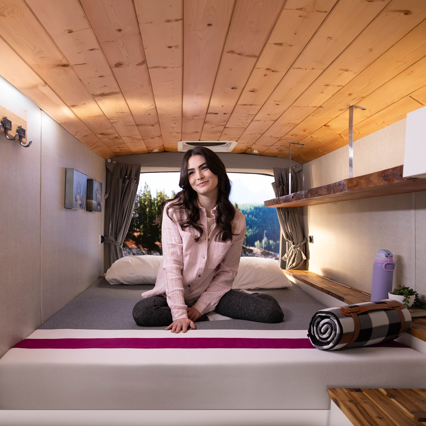 Woman sitting on a Juno RV hybrid Cool+ mattress inside a camper van