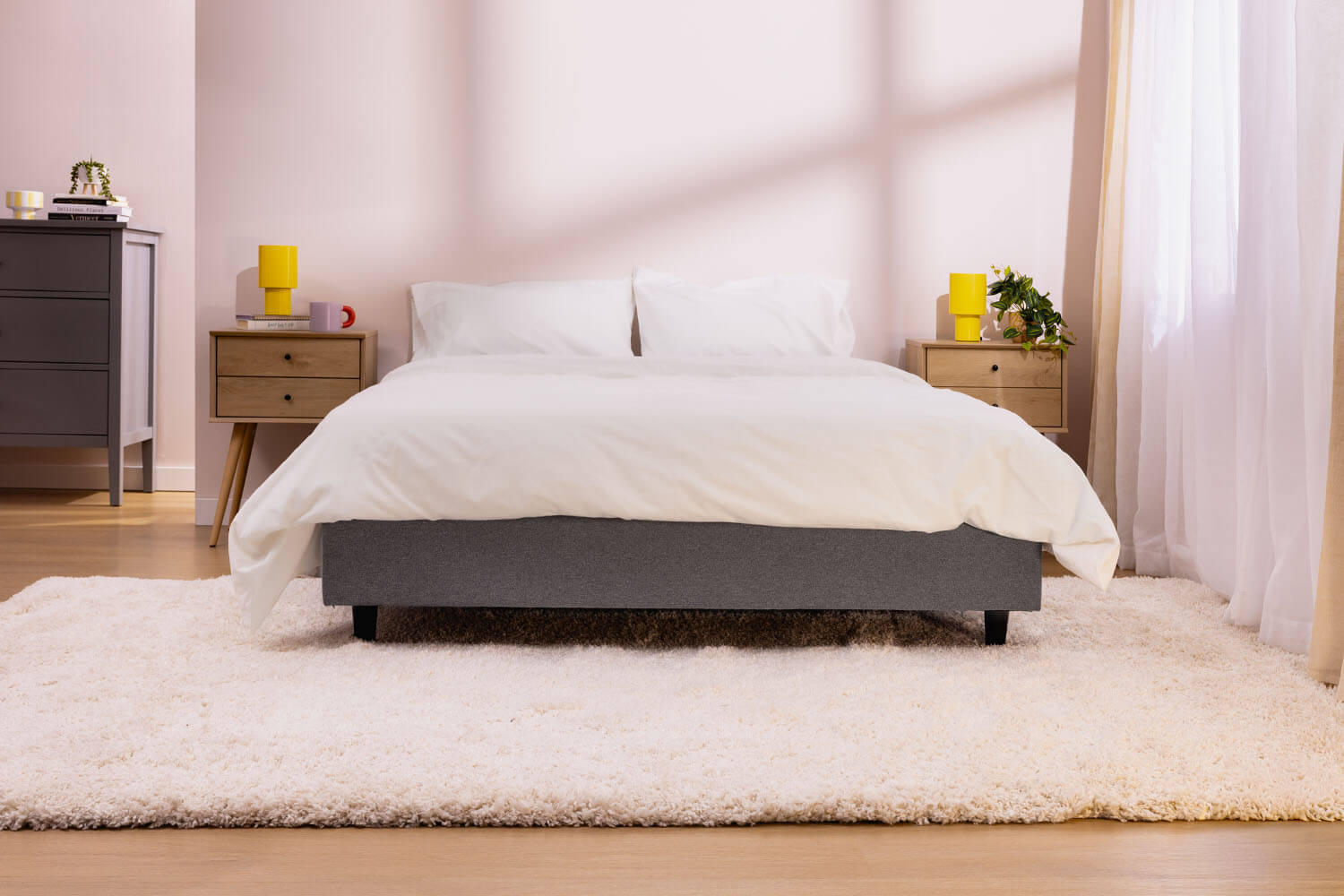 Matelas avec literie complète sur la base de lit plateforme, dans une chambre moderne et chaleureuse.