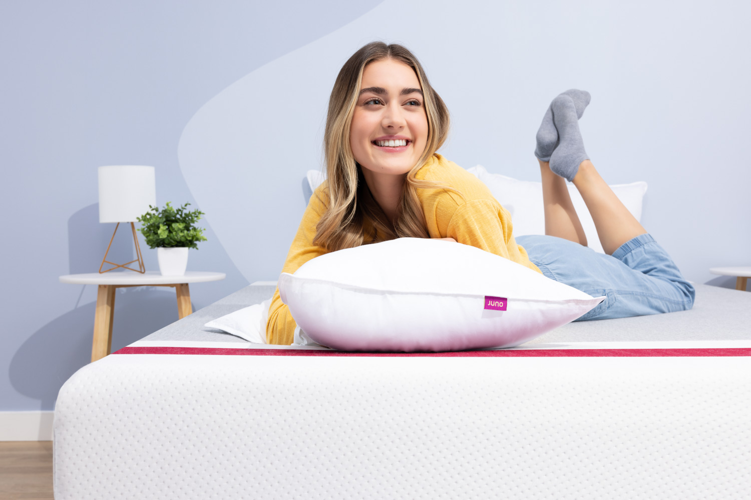 Woman smiling while she rests on her Juno Down Alternative Pillow