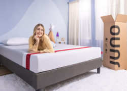Woman lying on a Juno mattress with the opened Juno box to the right