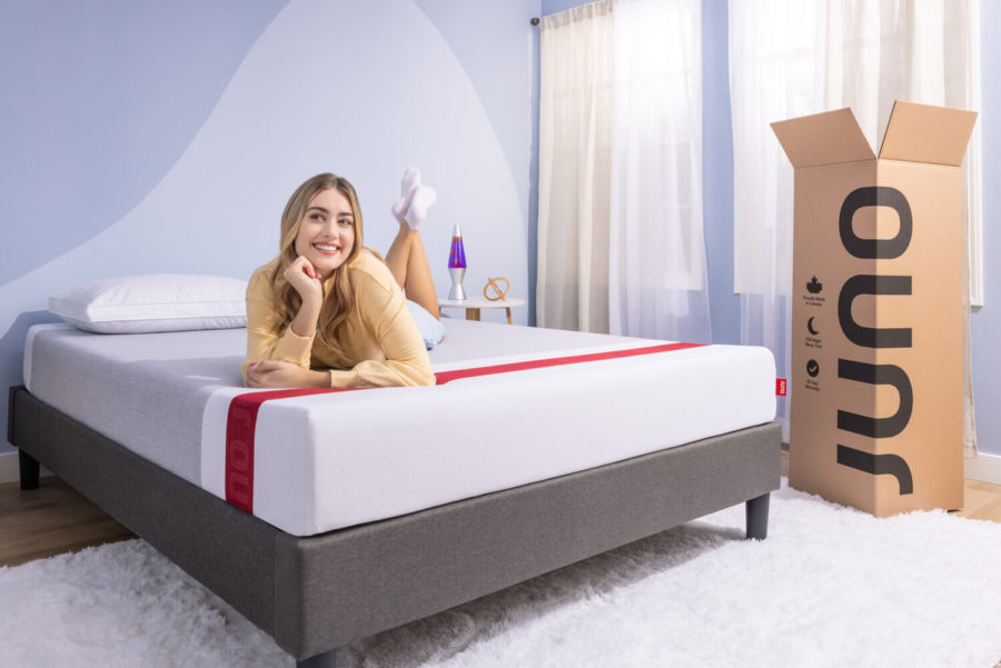 Woman lying on a Juno mattress with the opened Juno box to the right