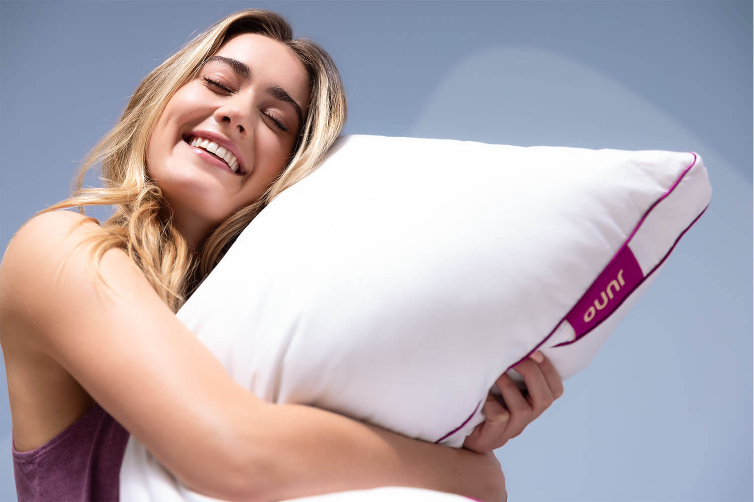 Woman smiling and hugging her Juno Adjustable Memory Foam Pillow